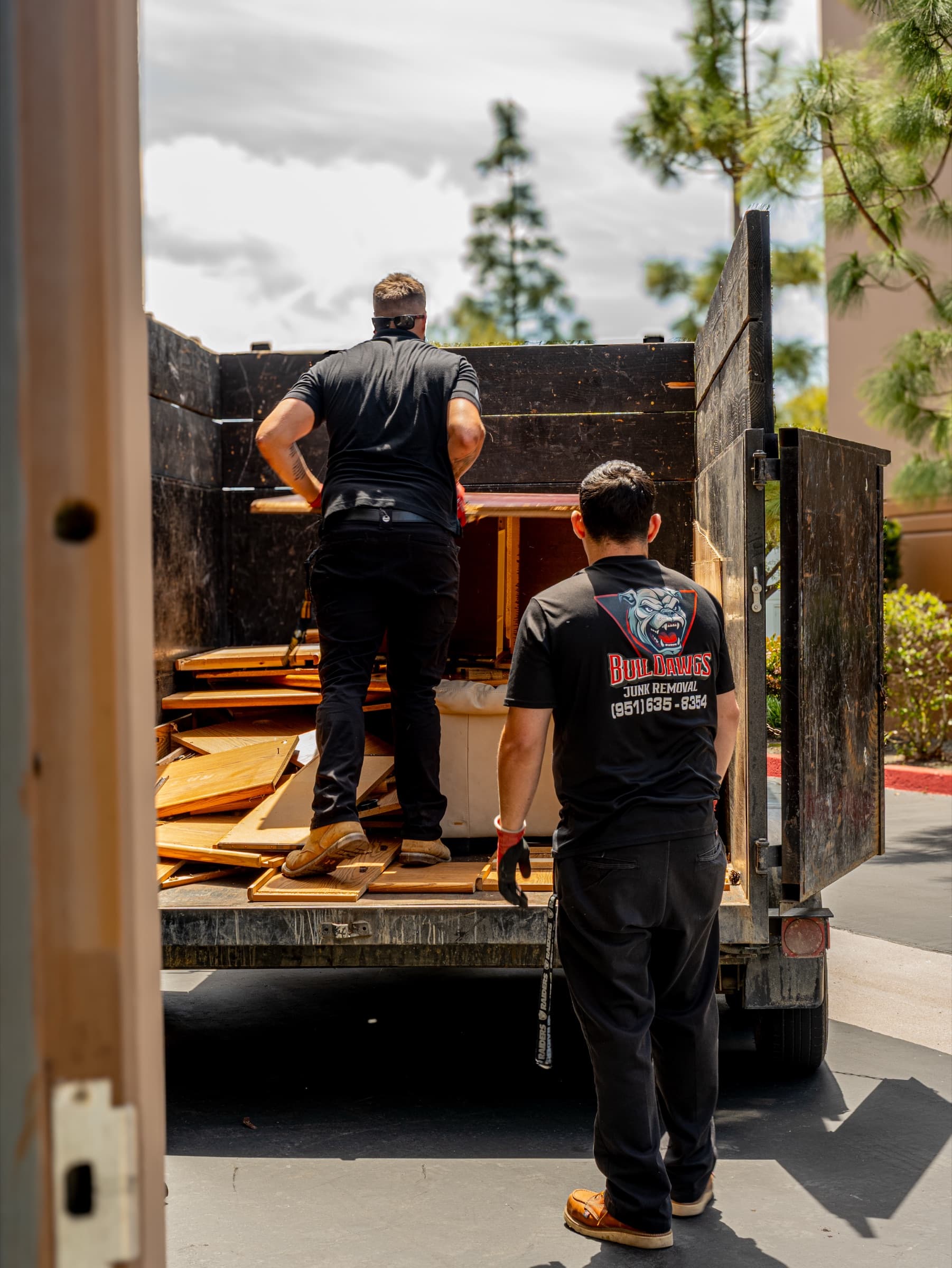BullDawgs crew loading scrap wood into a junk-hauling truck during a residential haul