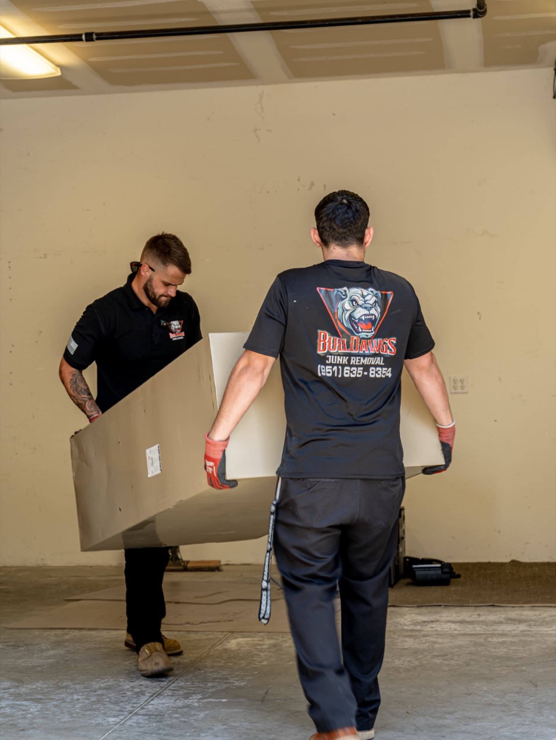 BullDawgs crew carrying a large cabinet out of a garage during a furniture-removal job