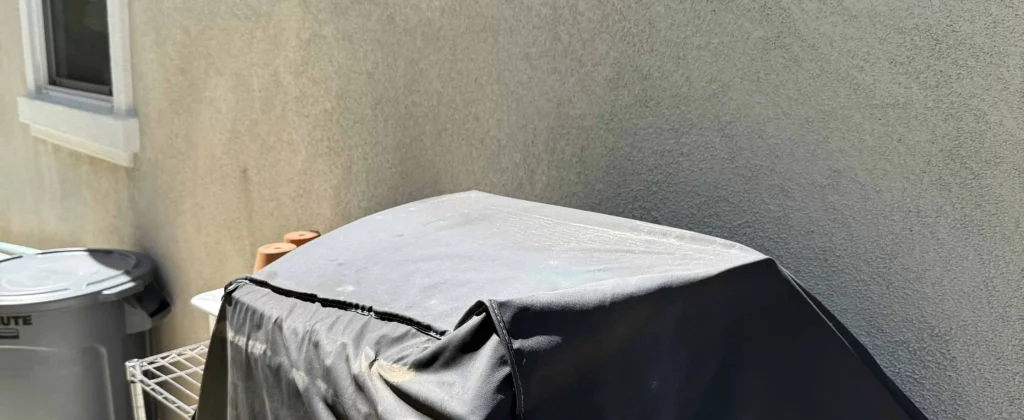 Covered grill and trash bins outside home after junk cleared