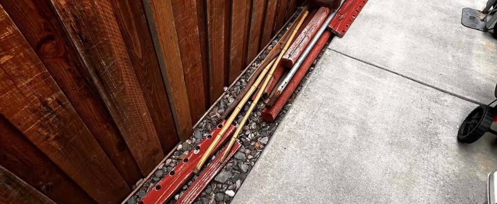 Old metal rods and pipes stacked along fence for disposal